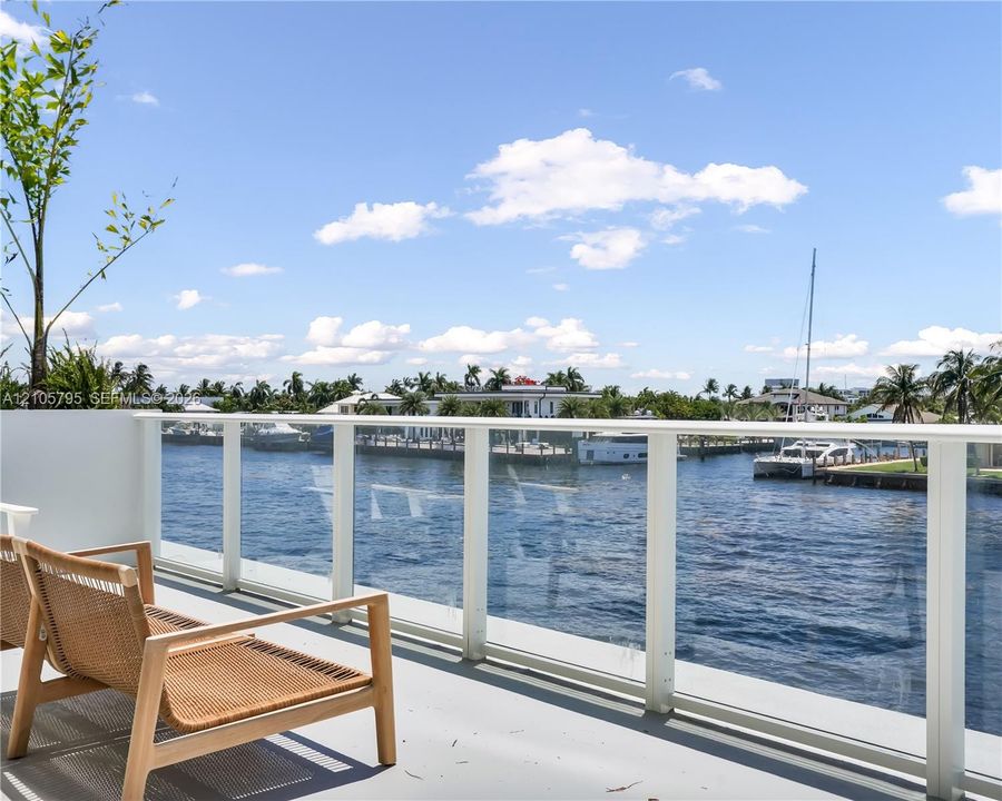 Elevated terrace featuring a water-facing glass panel railing and direct waterfront positioning