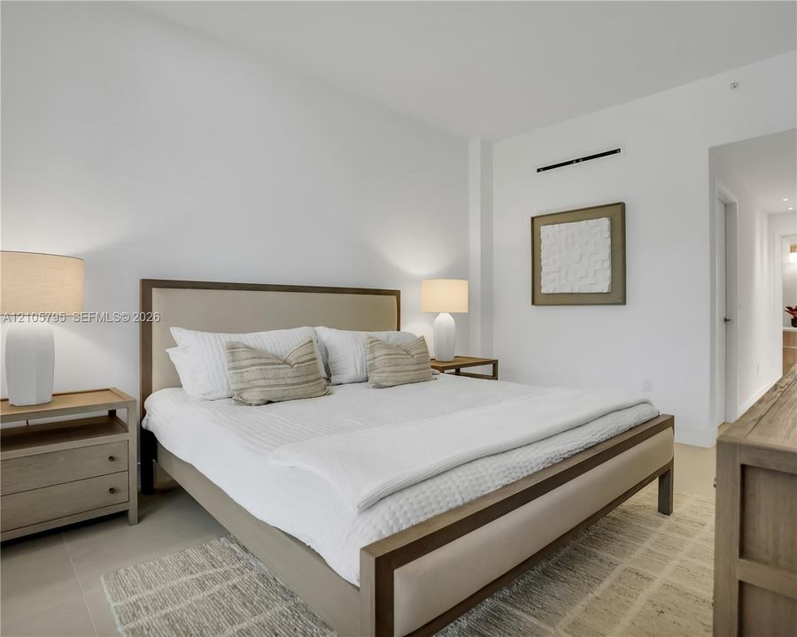 Neutral-toned interior featuring smooth wall surfaces, high ceilings, large-format tile flooring, and a wall-mounted climate control unit