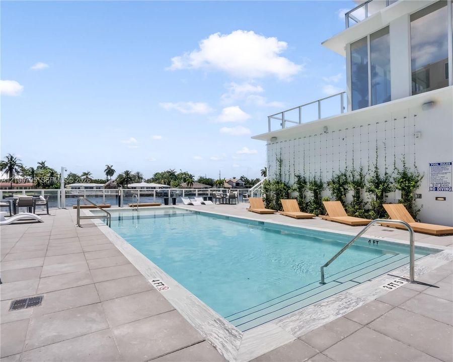Rectangular swimming pool featuring stone-tile decking, metal railings, and a water-level finish