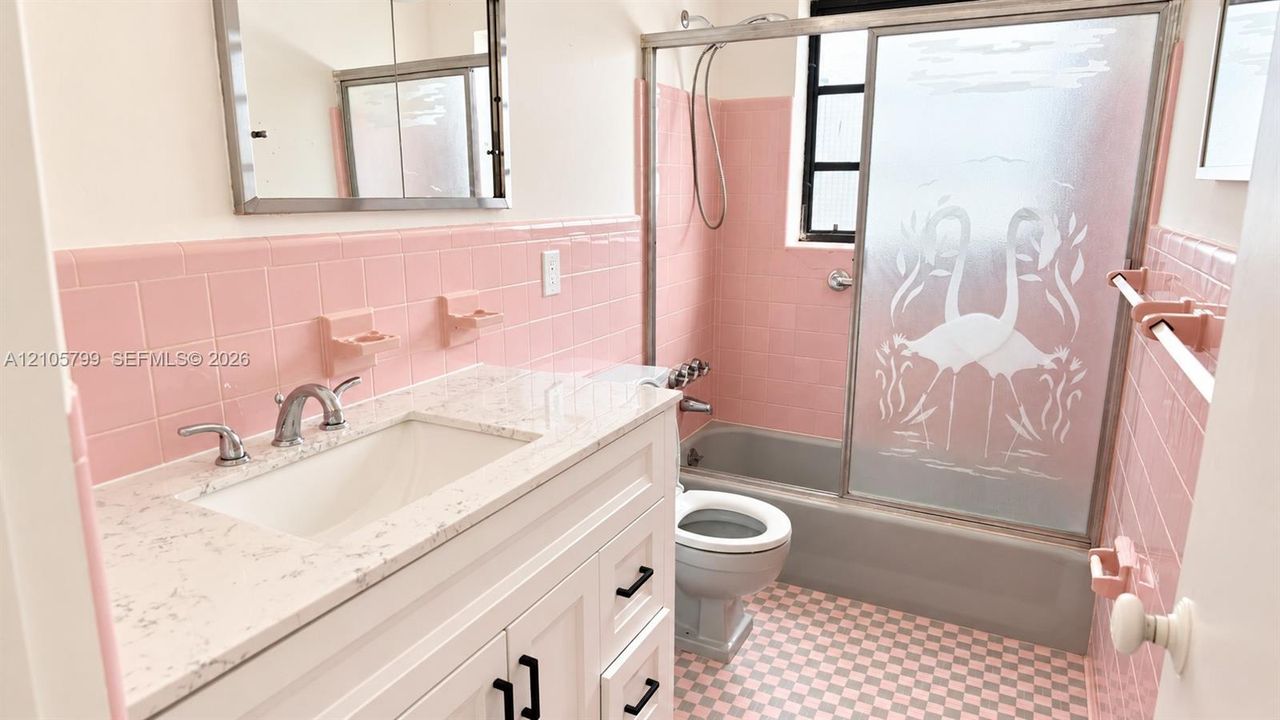 Bathroom featuring a white vanity with a composite countertop, ceramic wall tiling, a bathtub with an etched-glass sliding door, and checkered flooring