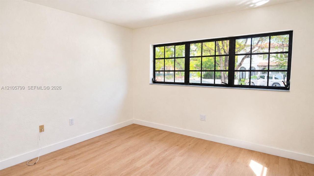 Neutral-toned wall finish featuring wood-finish flooring and a multi-pane window with a black frame