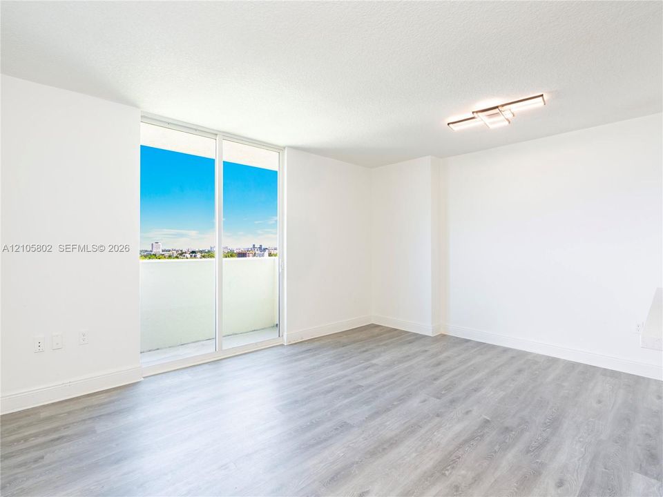 Open living area featuring floor-to-ceiling glass sliding doors, wood-finish flooring, and modern flush-mount overhead lighting