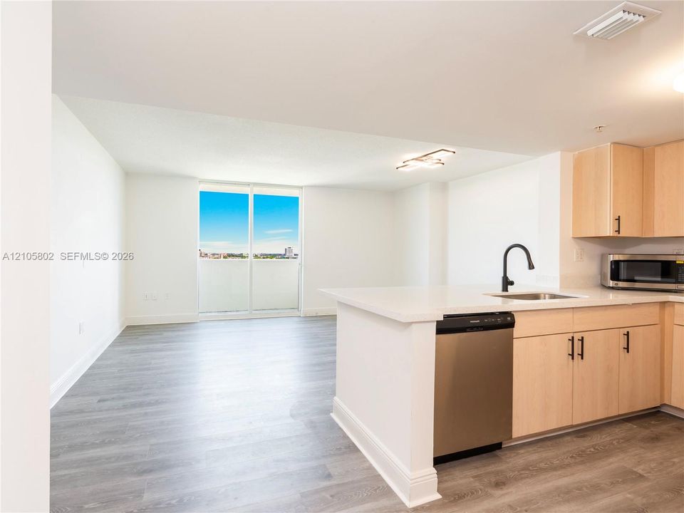 Kitchen featuring light-finish cabinetry, stone-surface countertops, stainless steel appliances, a matte black faucet, and wood-finish flooring