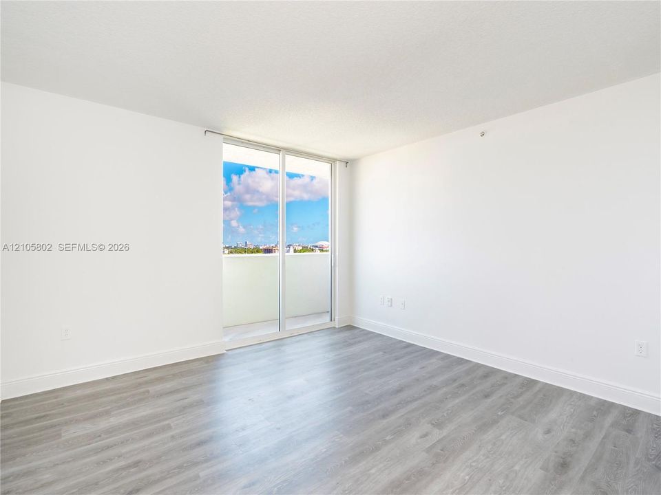 Interior space featuring wood-finish flooring, white walls, and floor-to-ceiling sliding glass doors providing outdoor access