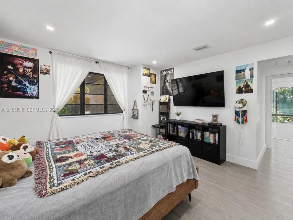 Neutral-toned wood-finish flooring, recessed lighting, and expansive window with dark-framed panes