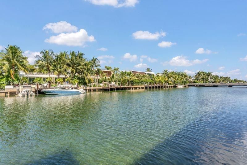 Waterfront estate featuring private boat dockage, expansive shoreline frontage, and mature palm landscaping