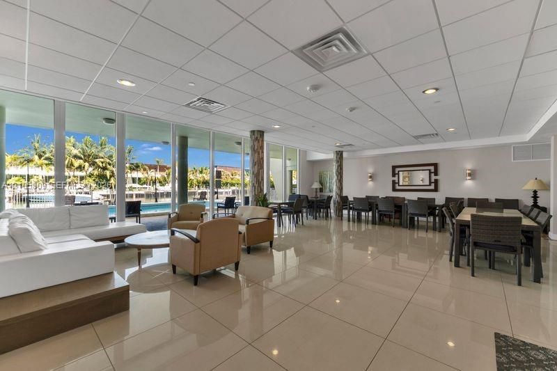 Expansive common area featuring large-format tile flooring, floor-to-ceiling windows, recessed lighting, and stone-clad support pillars