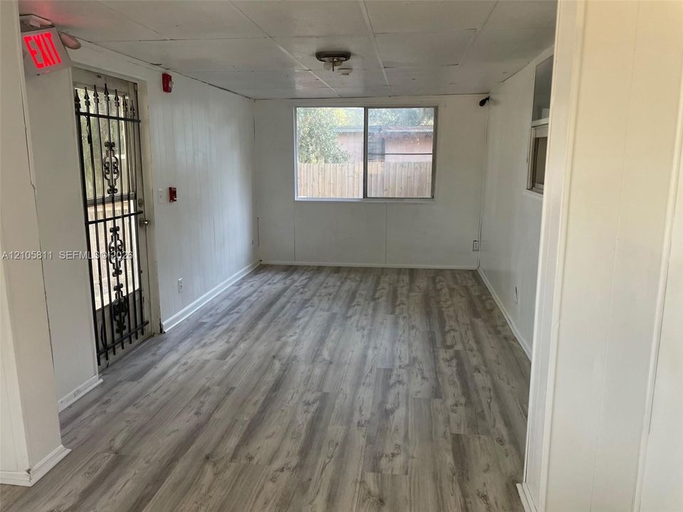 Interior space featuring wood-finish flooring, a metal security screen door, and a single-pane window