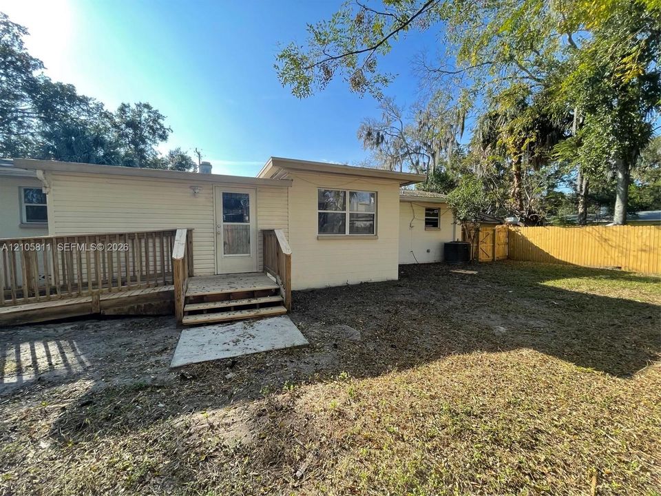 Exterior of home featuring beige siding, wood-finish ramp, wood-finish staircase, and fenced outdoor area
