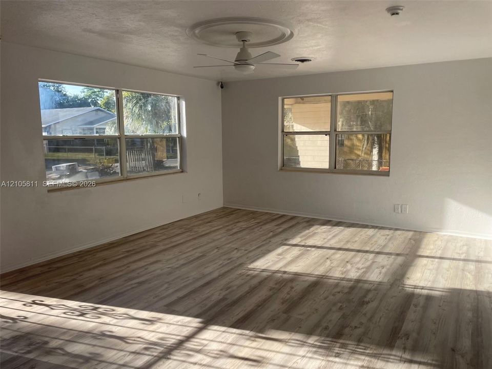 Interior space featuring wood-finish flooring, white walls, dual windows, and a ceiling-mounted fan with a decorative medallion