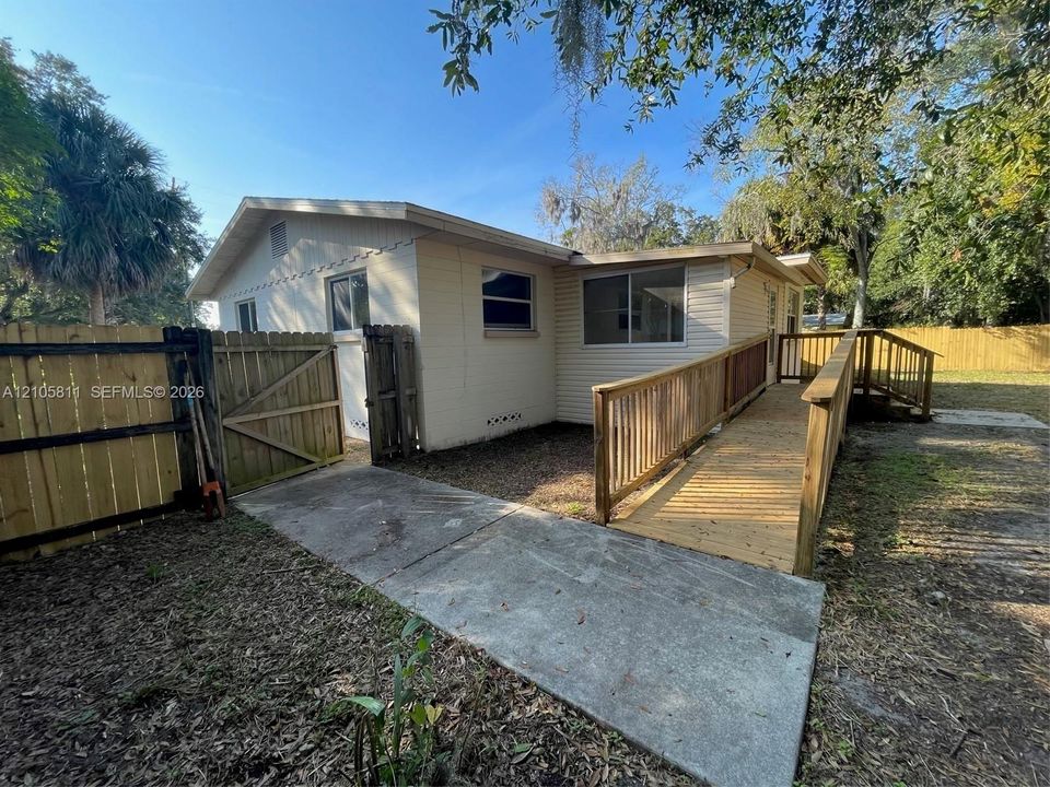 Exterior siding, fenced backyard, concrete pathway, and wooden ramp with railing