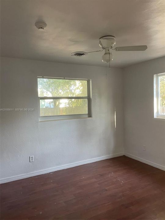 Interior space featuring wood-finish flooring, two dual-pane windows, and a ceiling fan with integrated lighting