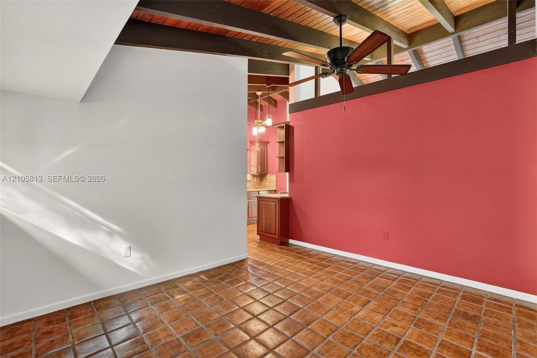 Exposed wood ceiling beams, vaulted ceiling, ceramic tile flooring, and a ceiling fan