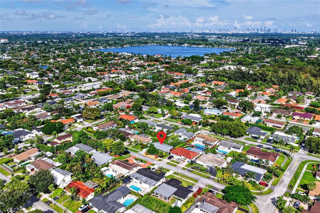 Aerial perspective featuring an established residential community with mature trees and proximity to a large inland lake and distant city skyline