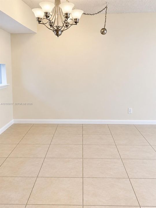 Neutral-toned ceramic tile flooring paired with a multi-arm chandelier featuring frosted glass shades and a metallic finish