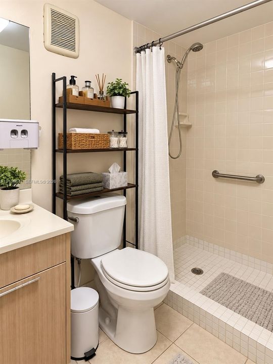 Bathroom featuring a light wood-finish vanity, solid-surface countertop with integrated sink, walk-in shower with square tile surround, and a wall-mounted metal grab bar