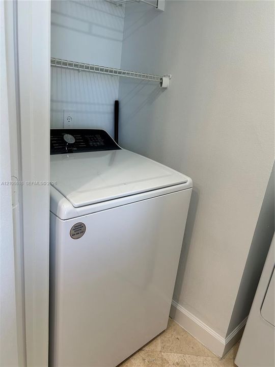 Laundry alcove featuring a top-load washer, white metal wire shelving, and neutral tile flooring