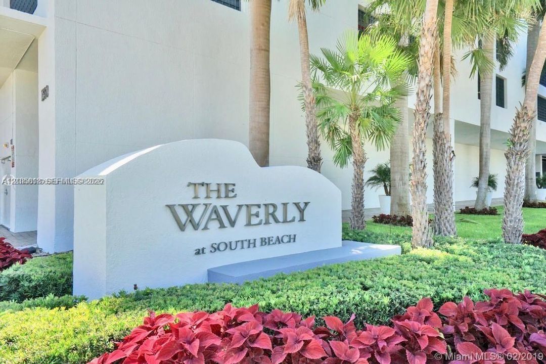 Sculpted concrete monument signage featuring metallic lettering, complemented by mature palm trees and professional manicured landscaping