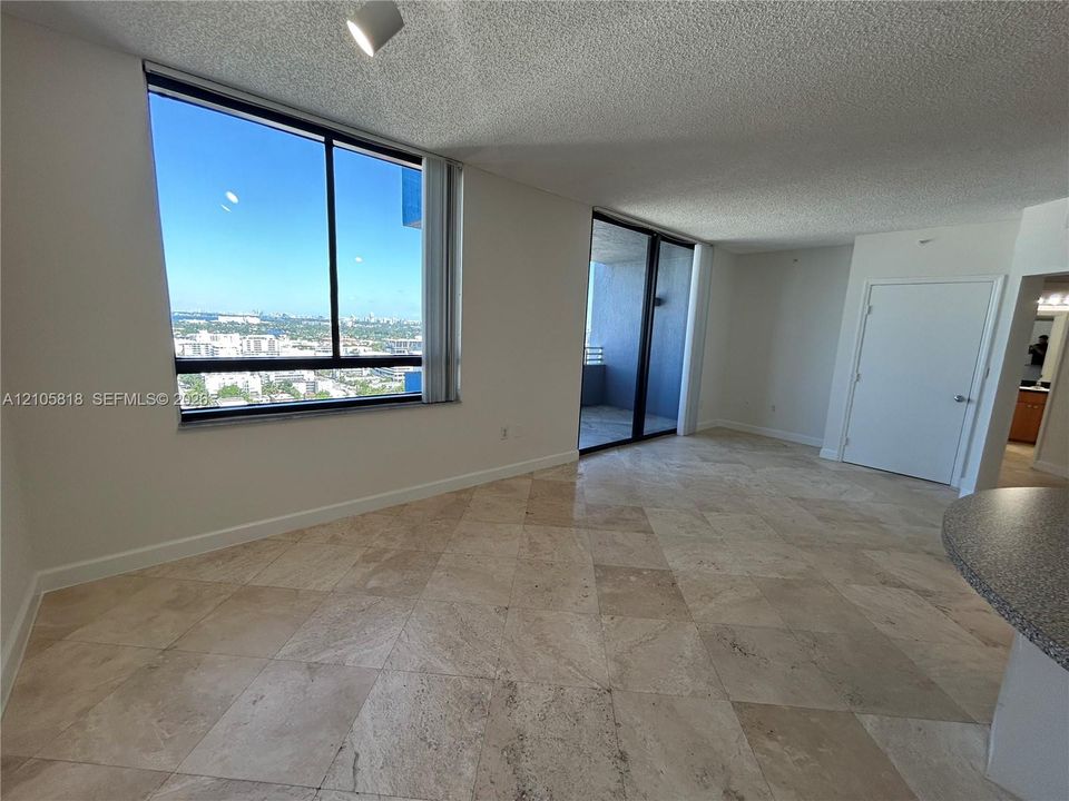 Interior space featuring large-format diagonal tile flooring, floor-to-ceiling windows, sliding glass door to a balcony, and overhead recessed track lighting