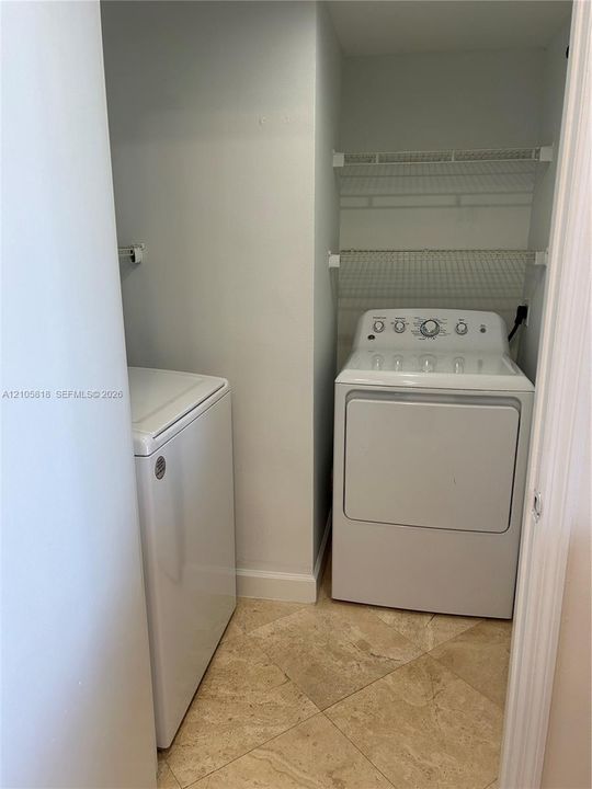 Laundry area featuring stone-tile flooring and installed wire shelving