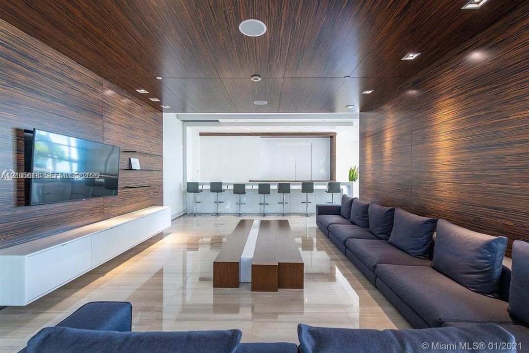 Interior space featuring horizontal wood-finish wall and ceiling paneling, polished stone flooring, recessed lighting, and a built-in wall-mounted media console