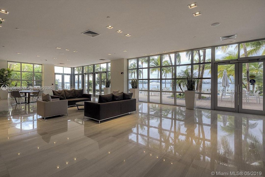 Expansive interior featuring polished stone flooring, floor-to-ceiling glass wall panels, and recessed ceiling lighting