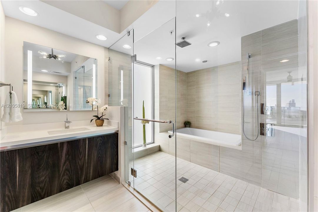 Primary Bathroom with Dual Backlit Sinks, Glass enclosed Shower & Tub as well as Hidden Water Closet.