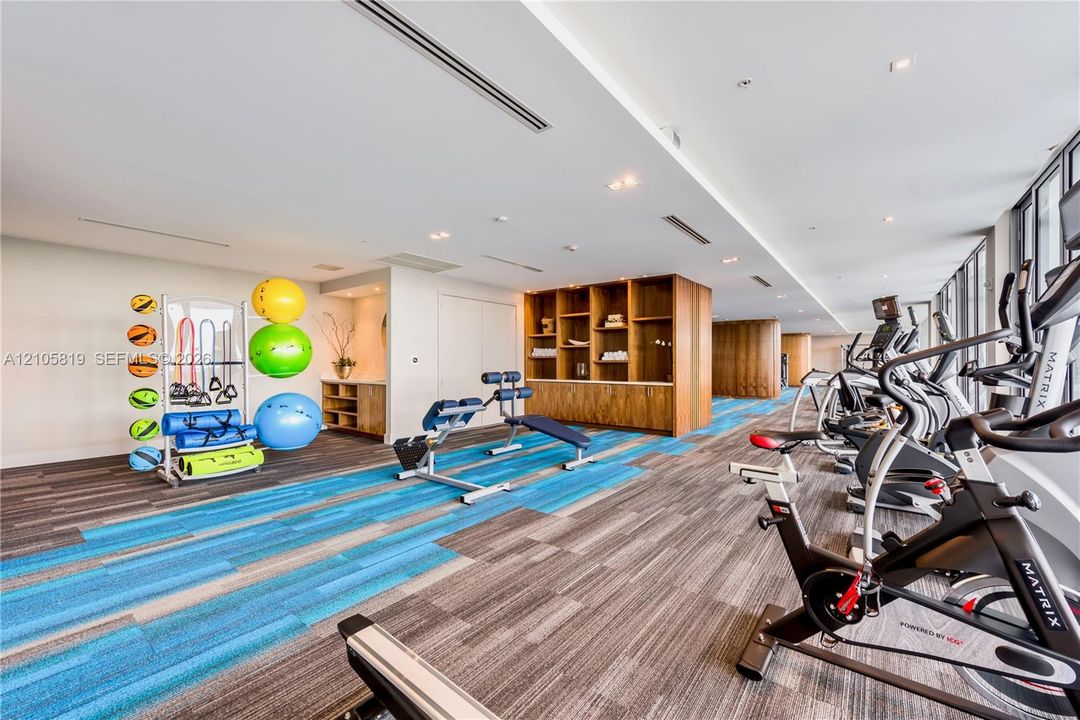 Fitness center featuring recessed lighting, patterned carpeting, built-in wooden shelving, and expansive floor-to-ceiling windows