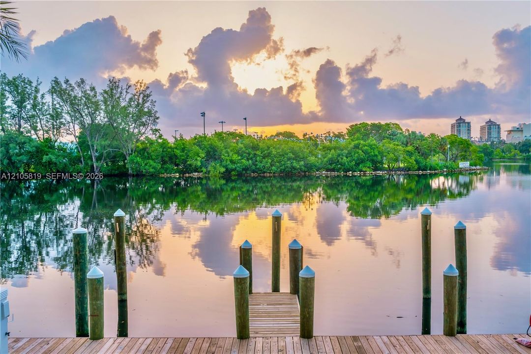 Sunrise on the 400' Waterfront dock featuring wooden decking and vertical mooring pilings overlooking a natural canal and lush foliage