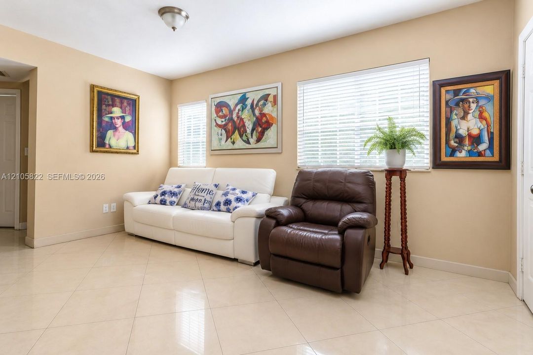 Large-format tile flooring, neutral wall tones, and horizontal window blinds featuring natural light