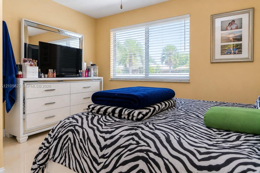Neutral-toned interior space featuring light-colored tile flooring and a horizontal window fitted with Venetian blinds