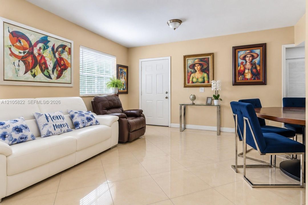 Neutral-toned interior space featuring polished tile flooring, white six-panel entry door, and horizontal blinds