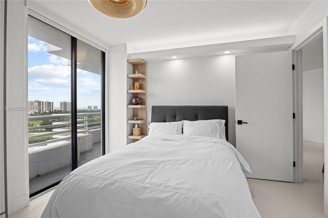 Floor-to-ceiling sliding glass door, recessed lighting, built-in recessed shelving, neutral tile flooring, and access to a private balcony