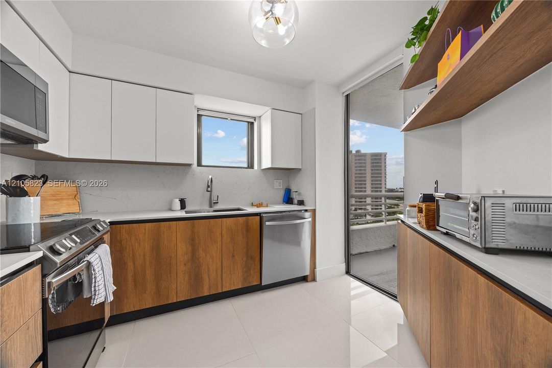 Kitchen featuring two-tone cabinetry with wood-finish lower units and white upper cabinets, quartz countertops, stainless steel appliances, and integrated floating shelving