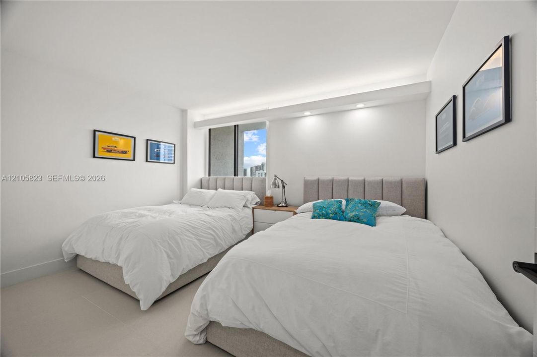 Neutral-toned interior space featuring recessed ceiling lighting, a soffit with integrated illumination, and large-format tile flooring