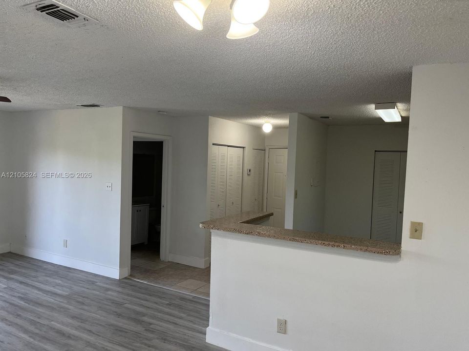 Interior space featuring wood-finish flooring, a stone-composite breakfast bar, multi-panel louvered closet doors, and neutral wall tones