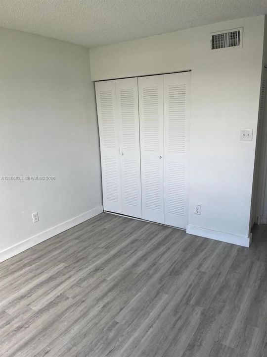 Wood-finish flooring paired with white louvered-style closet doors