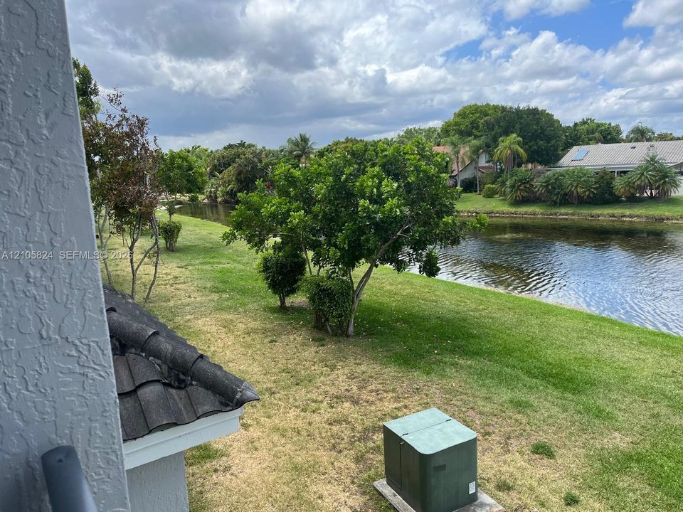 Waterfront backyard featuring a grass lawn, mature trees, and concrete tile roofing