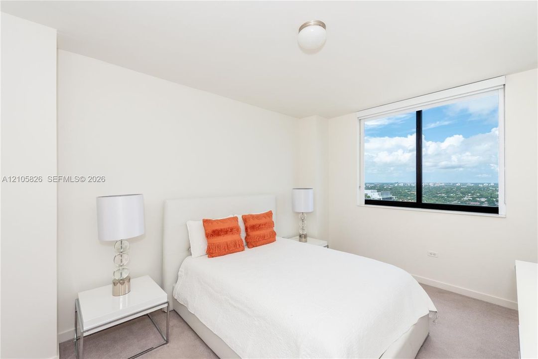 Neutral-toned interior featuring wall-to-wall carpeting, a large window with black framing, and a ceiling-mounted globe light fixture