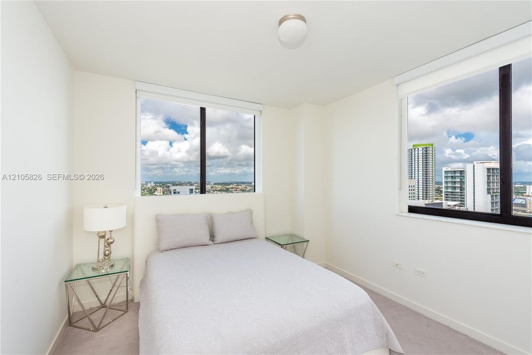 Room featuring neutral-toned carpeting, dual-aspect windows, and urban skyline backdrop