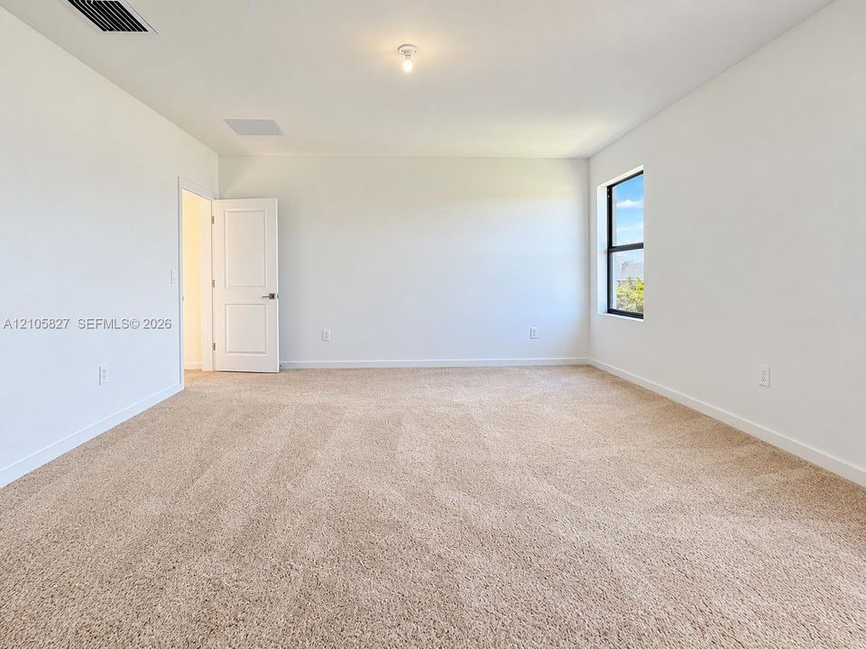 Neutral interior featuring plush wall-to-wall carpeting, crisp white walls, a single-hung window, and a paneled interior door