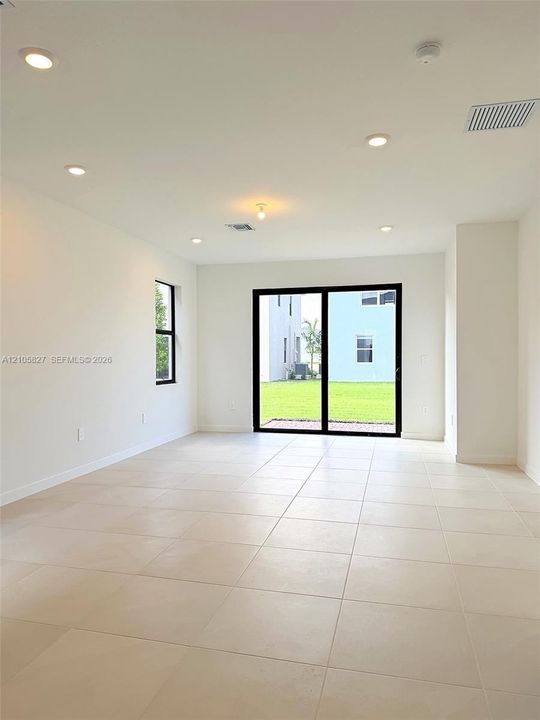 Large-format neutral tile flooring, recessed ceiling lighting, and expansive sliding glass doors opening to the exterior
