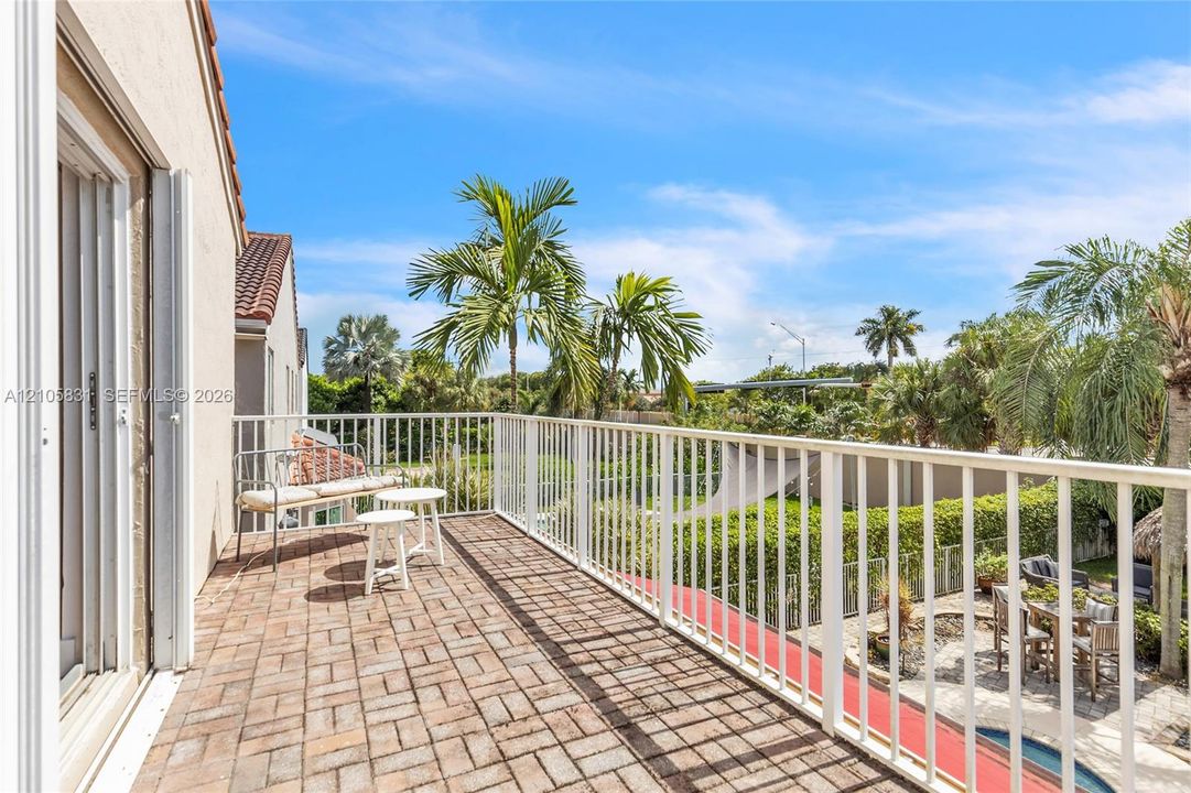 Elevated balcony featuring brick paver flooring, white metal railing, and sliding glass door access