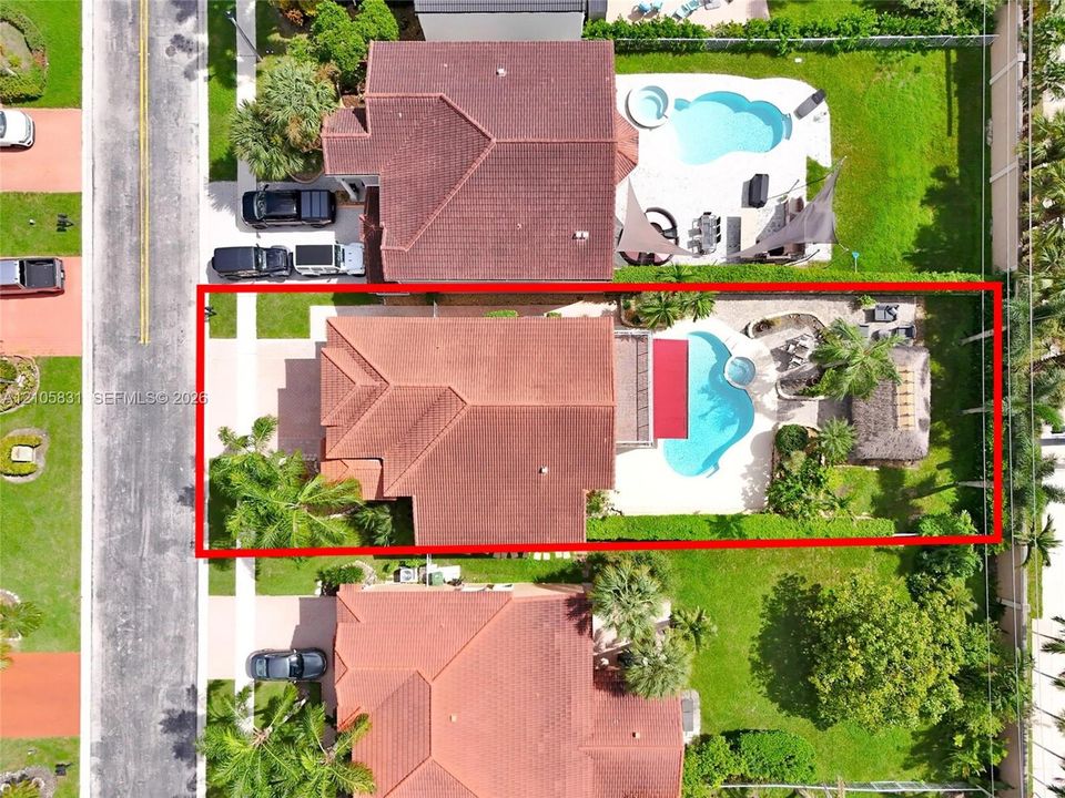 Aerial perspective of a property featuring a swimming pool, integrated spa, paved pool deck, and a detached palapa
