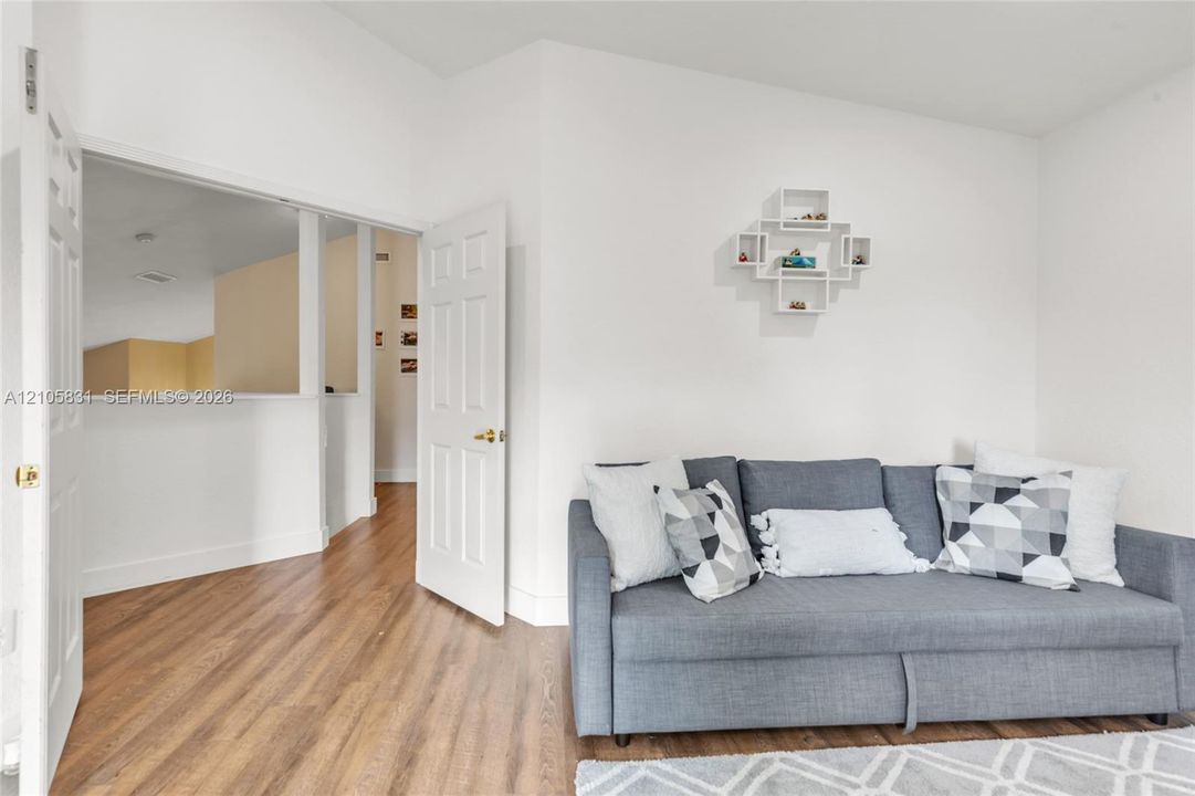 Room featuring wood-finish flooring, a six-panel interior door with brass hardware, and a built-in wall niche
