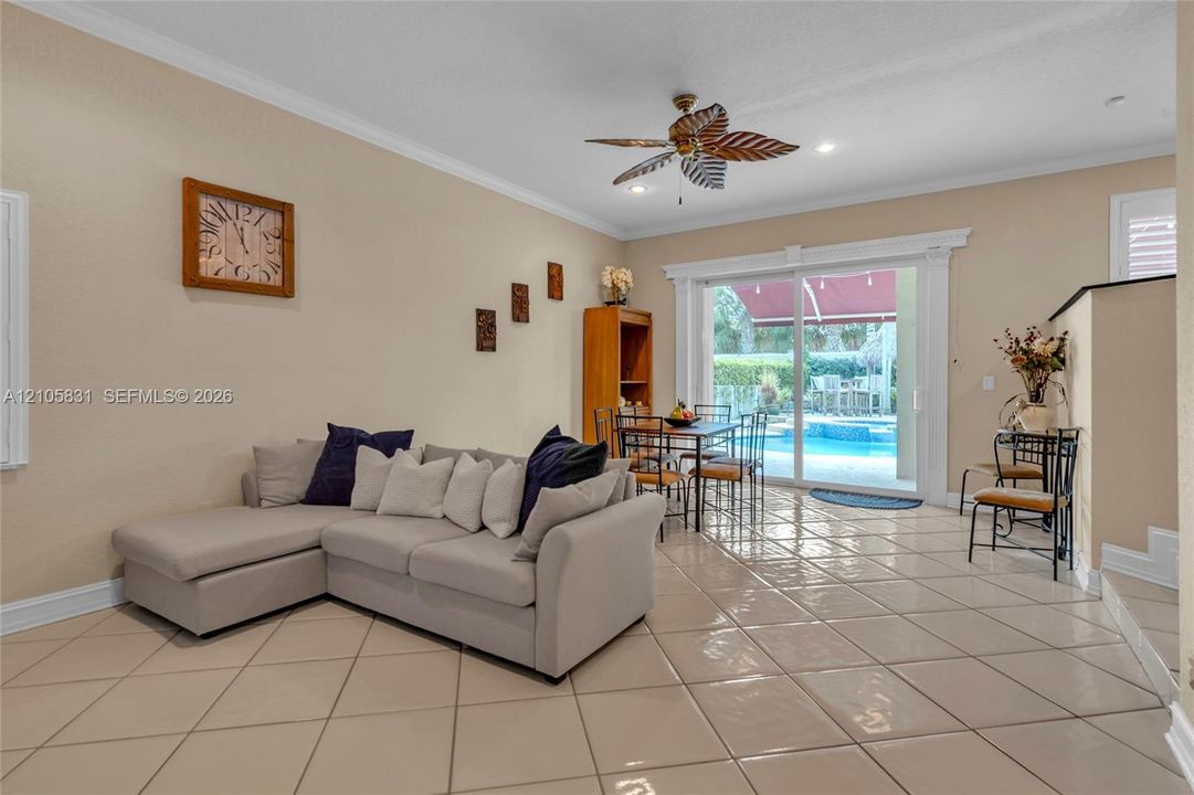 Large-format tile flooring, decorative ceiling fan with blade accents, and sliding glass doors featuring detailed trim molding