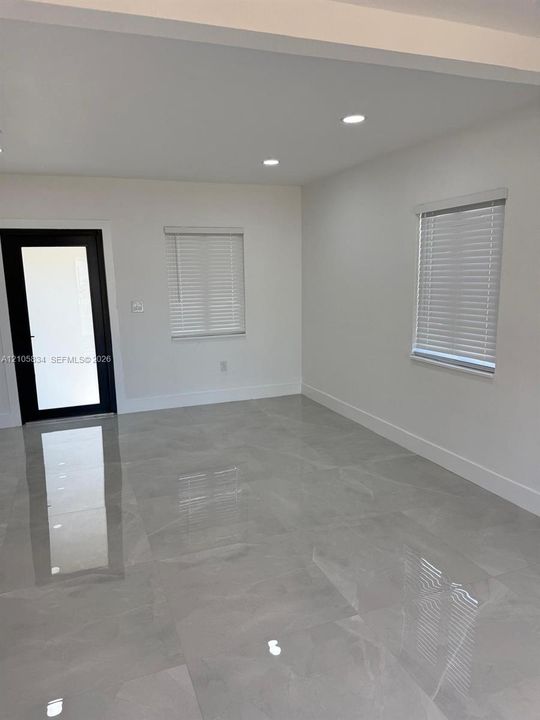 Interior space featuring polished stone-finish flooring, recessed lighting, white walls, and a black-framed glass panel door