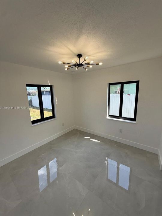 Interior room featuring large-format tile flooring, matte black window frames, and a multi-arm sputnik-style ceiling light fixture