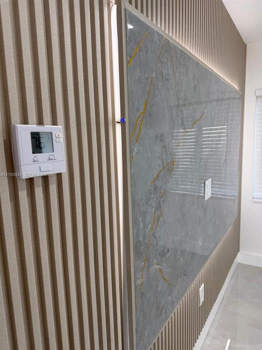 Vertical wood-slat wall paneling featuring a large, polished grey-and-gold veined stone-finish accent inlay with integrated perimeter lighting