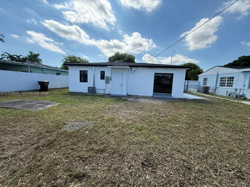 Exterior view featuring white masonry walls, a flat roofline, sliding glass doors, and a private fenced yard